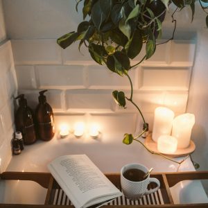 Relax in a cozy bathtub with candles, tea, and a book for a serene evening.