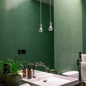 Contemporary bathroom featuring a green tiled wall, plants, sink, and towels.